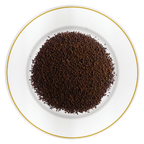 Close-up of Riverbeki Classic Assam Premium CTC Tea loose granules displayed on a white plate with gold rim, highlighting the bold rich CTC texture